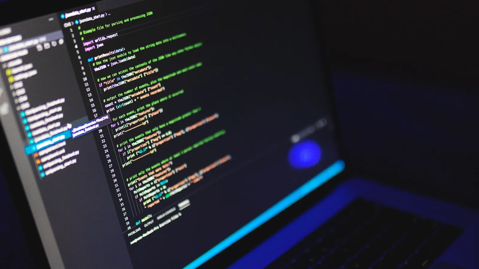 Laptop showing colourful source code in a dark room