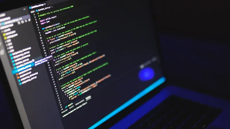 Laptop showing colourful source code in a dark room