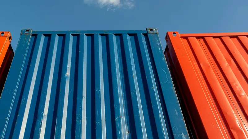 Blue and orange shipping containers against a blue sky